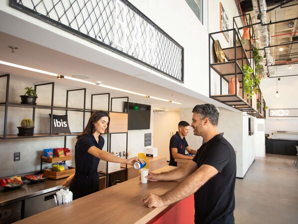 A modern bar area with a counter, shelves with plants, and a sign that reads 'ibis'.