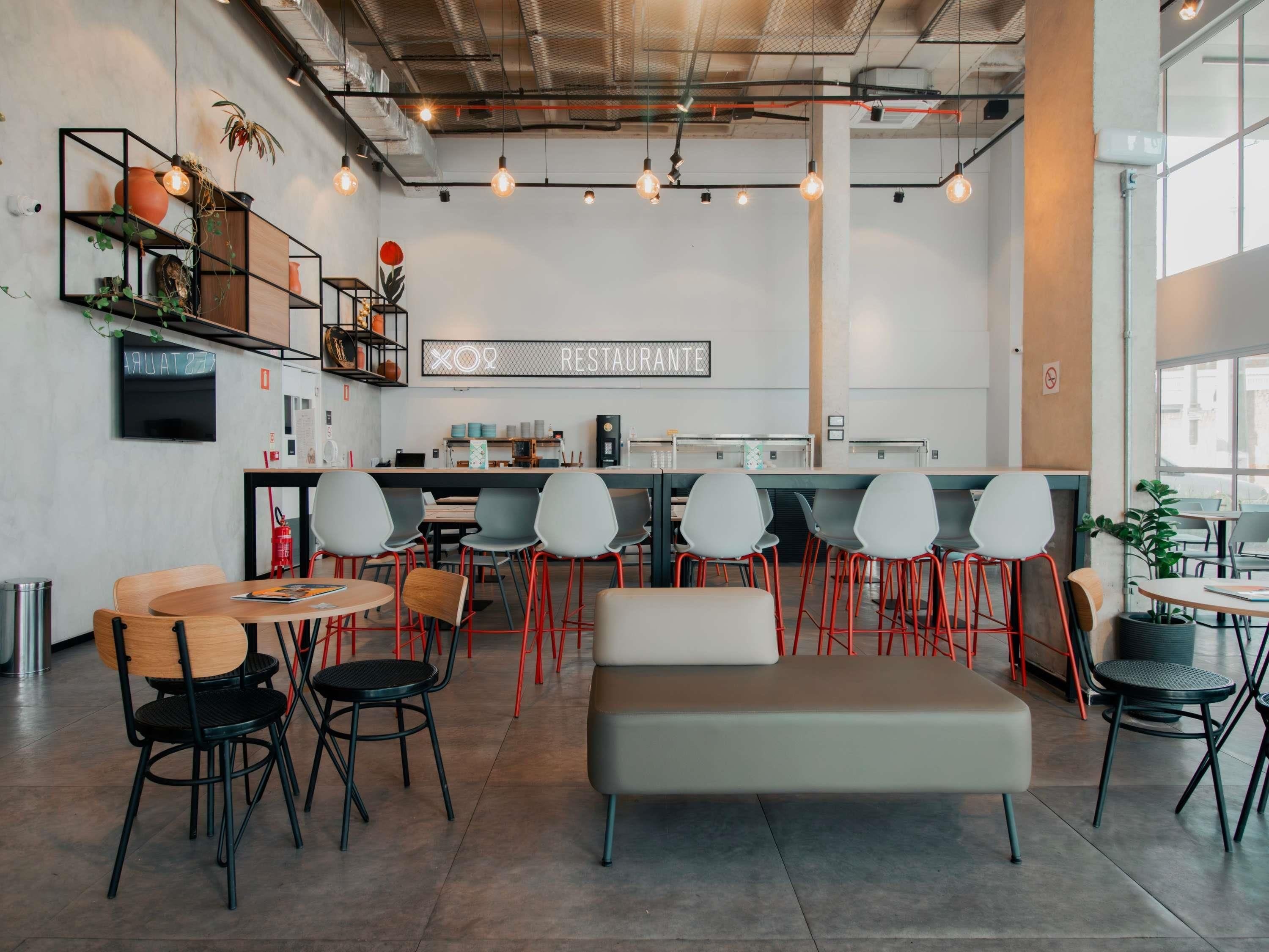 A modern cafe with a bar area, seating arrangements, and visible kitchen equipment.