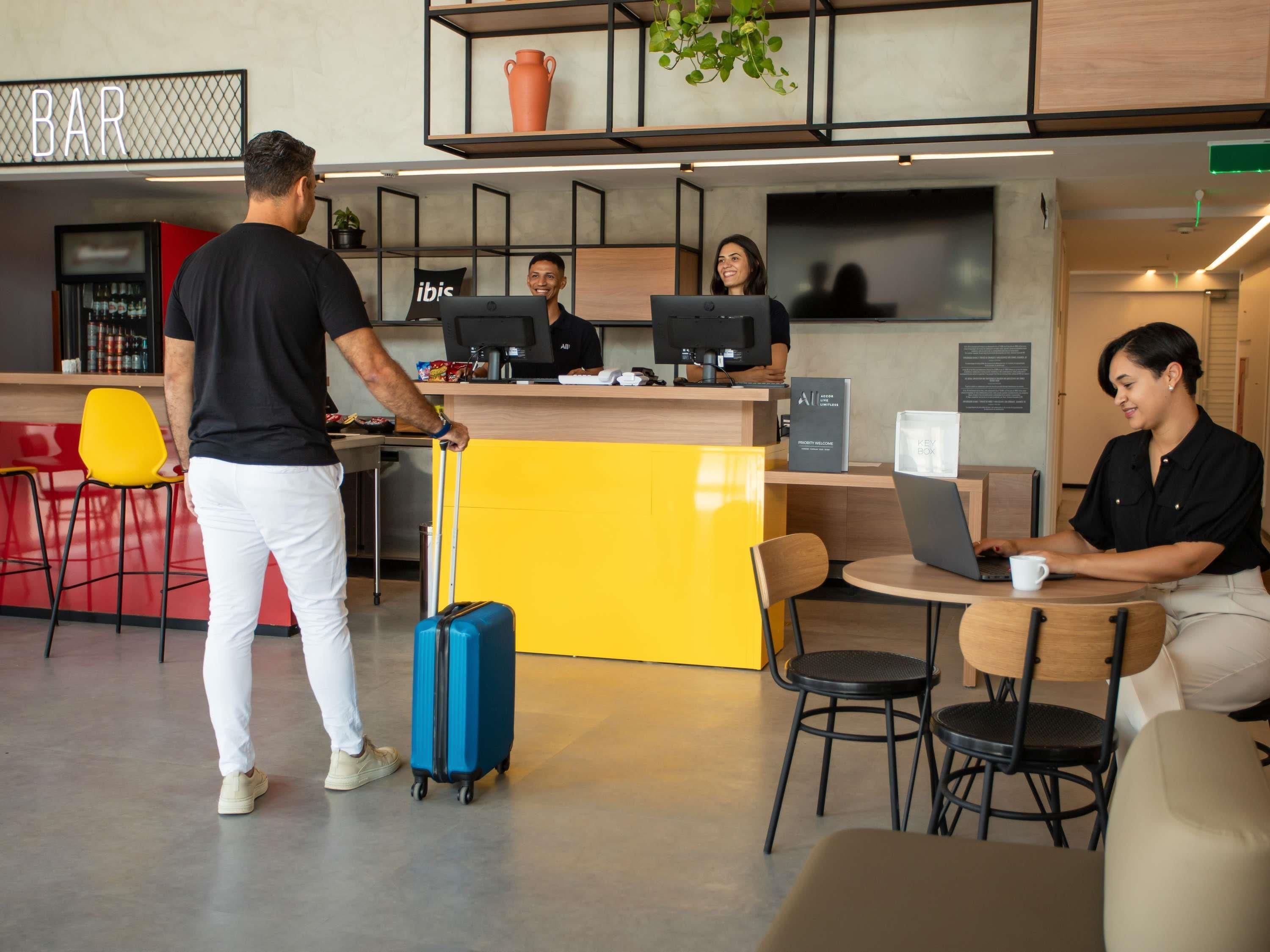 A hotel lobby with a reception desk, bar area, and seating.