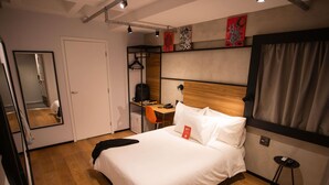 Une chambre d’hôtel comprenant un lit, un bureau, une chaise, un miroir et une armoire.