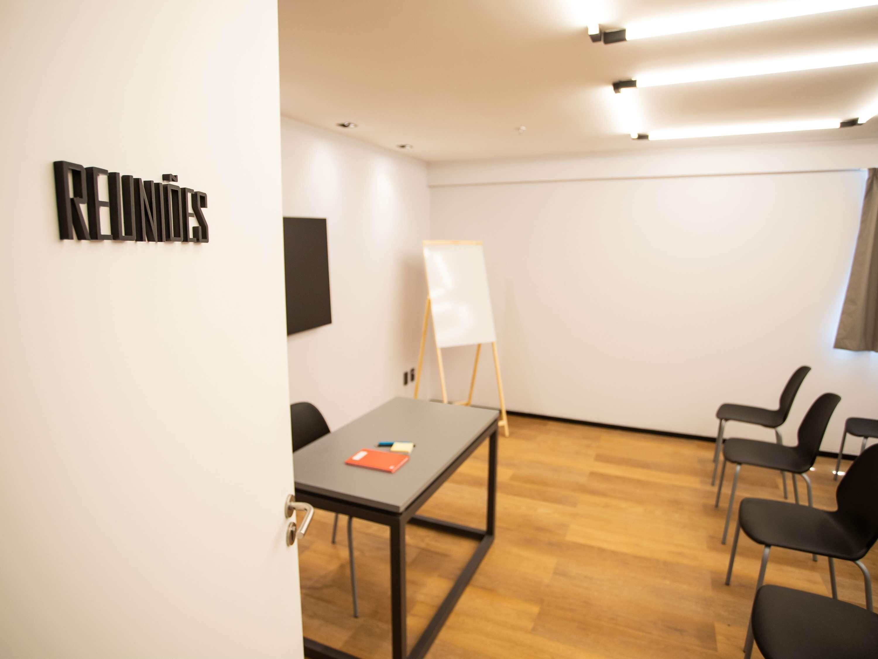 A conference room with a whiteboard, a table with chairs, and a sign on the wall.