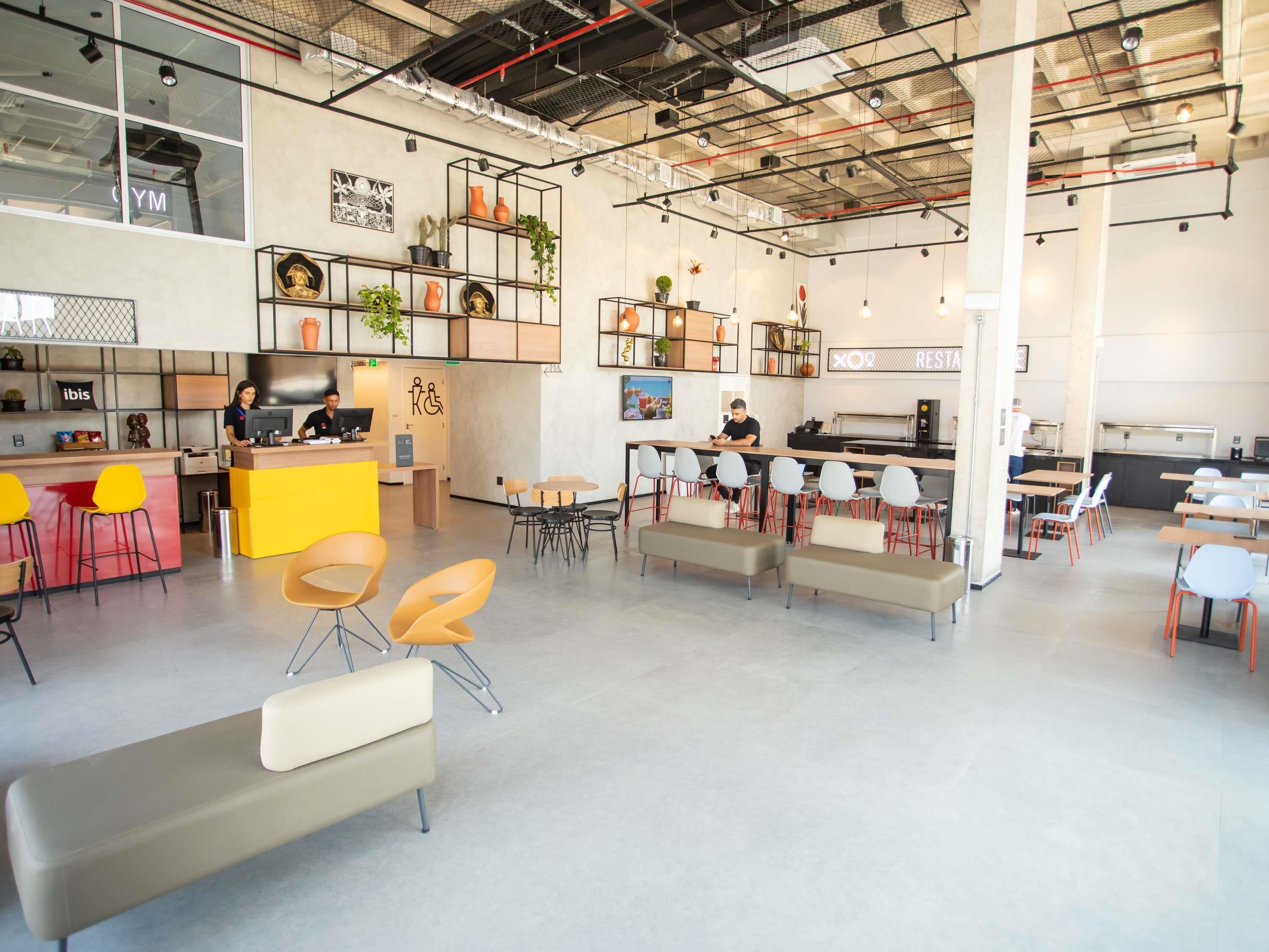A modern interior with a reception desk, seating areas, and a kitchenette.