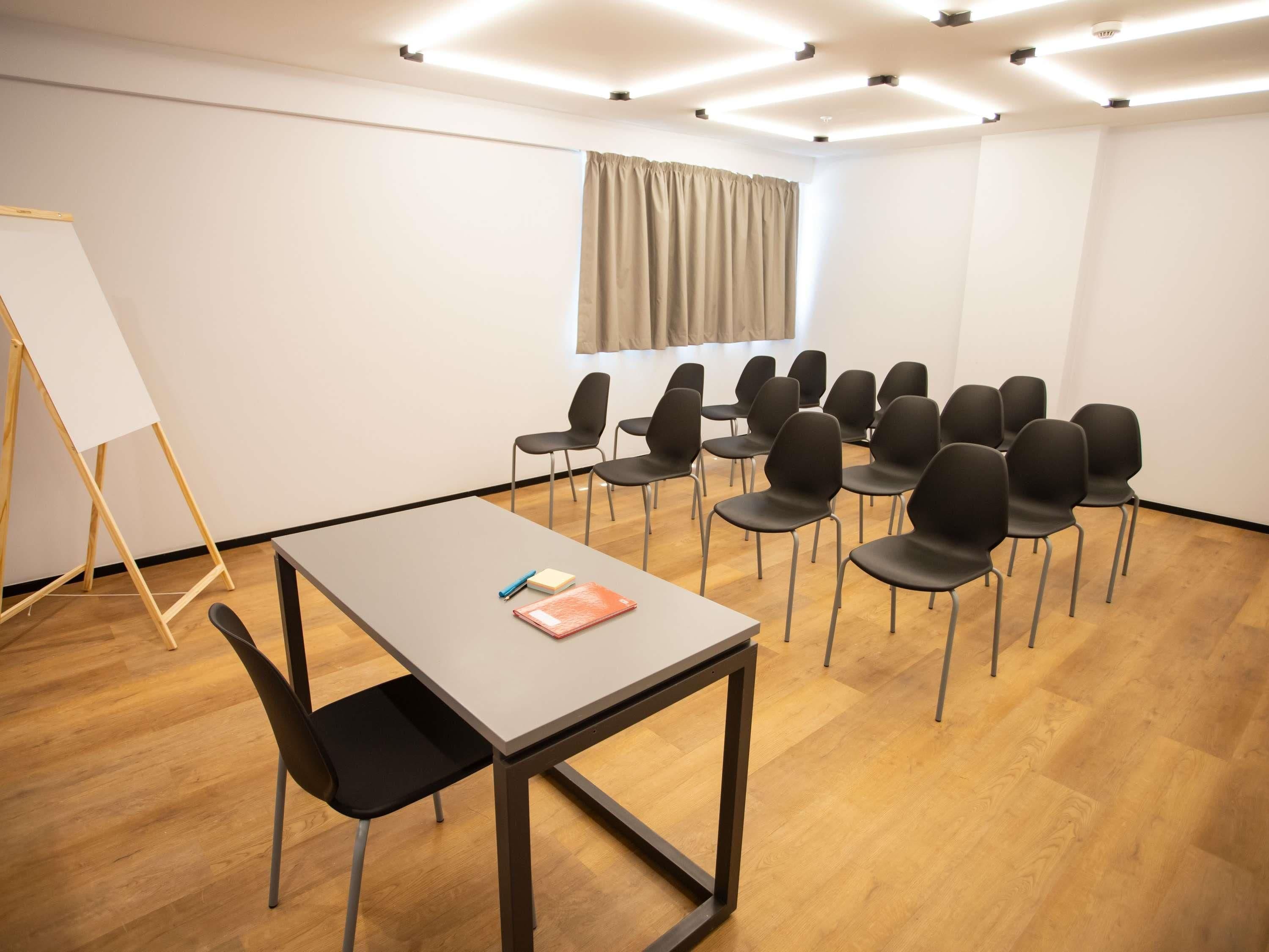A conference room with a table, chairs, a whiteboard, and a window with curtains.