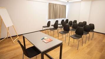 A conference room with a table, chairs, a whiteboard, and a window with curtains.