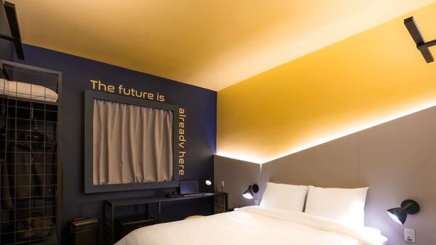 Una habitación de hotel moderna con una cama grande, un escritorio con una computadora portátil y un armario.