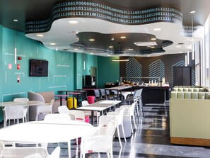 A modern interior with tables and chairs, a bar area, and a curved ceiling with binary code.