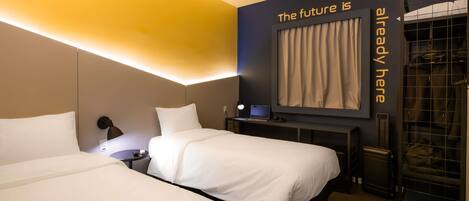 A hotel room with two beds, a desk, a laptop, and a large mirror on the wall.