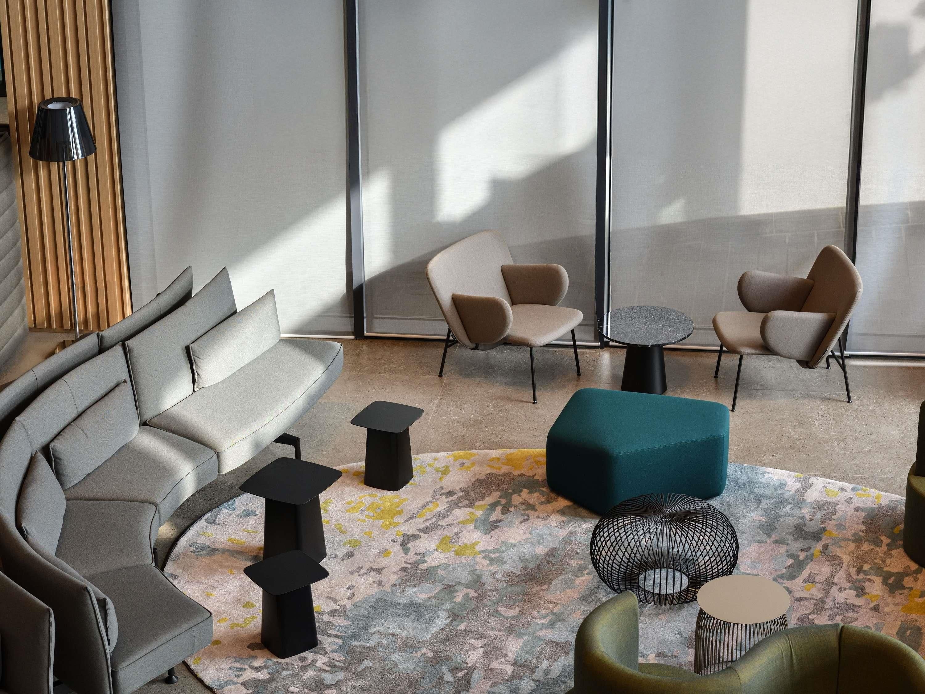 Un espace détente moderne comprenant un canapé, deux fauteuils, une table basse et un tapis à motifs.