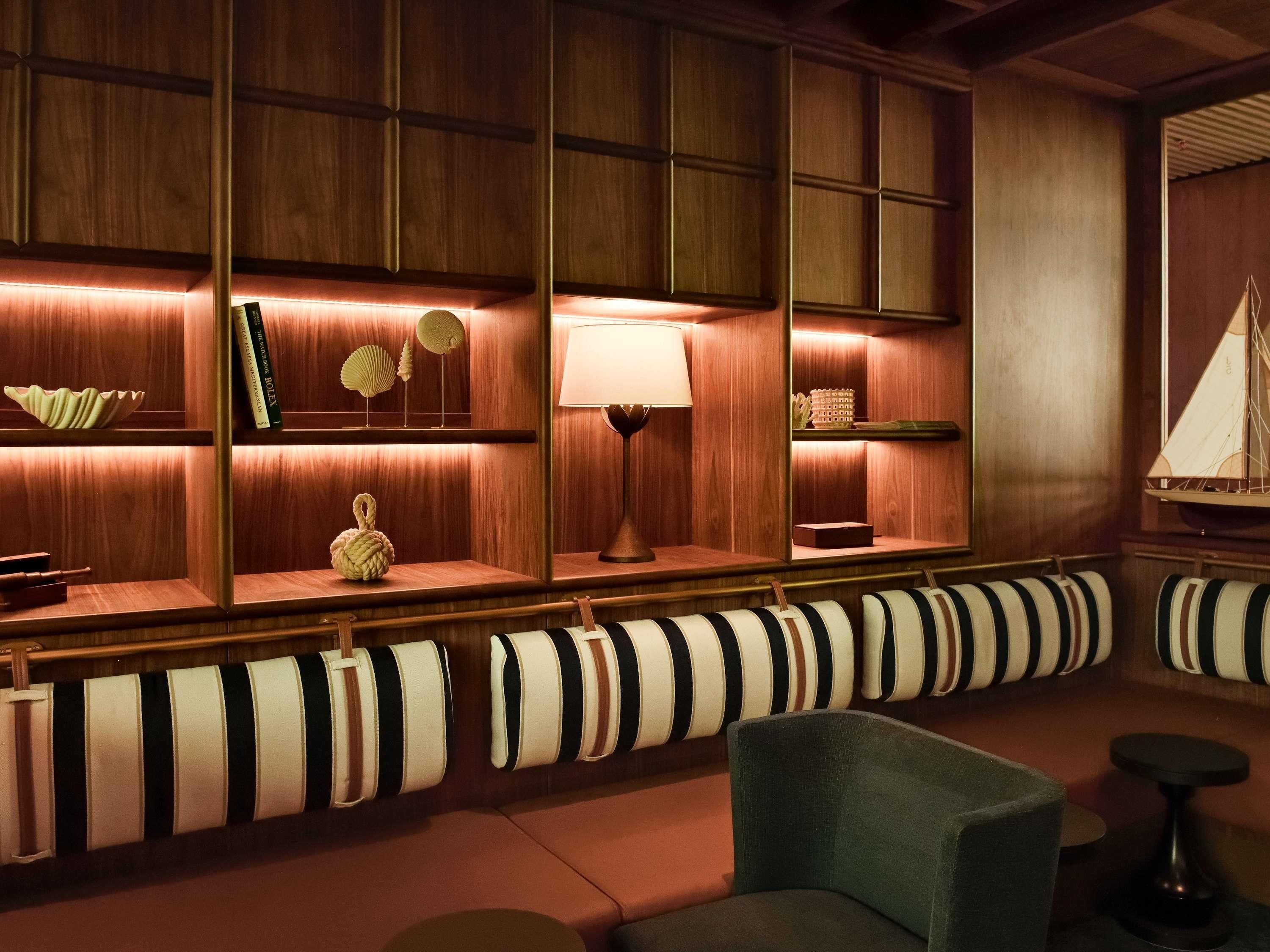 Cómoda sala de estar con sofás a rayas, estantes de madera con objetos decorativos y una pequeña mesa con una lámpara.