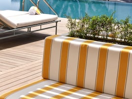 A poolside lounge area with a striped sofa and a sunbed.