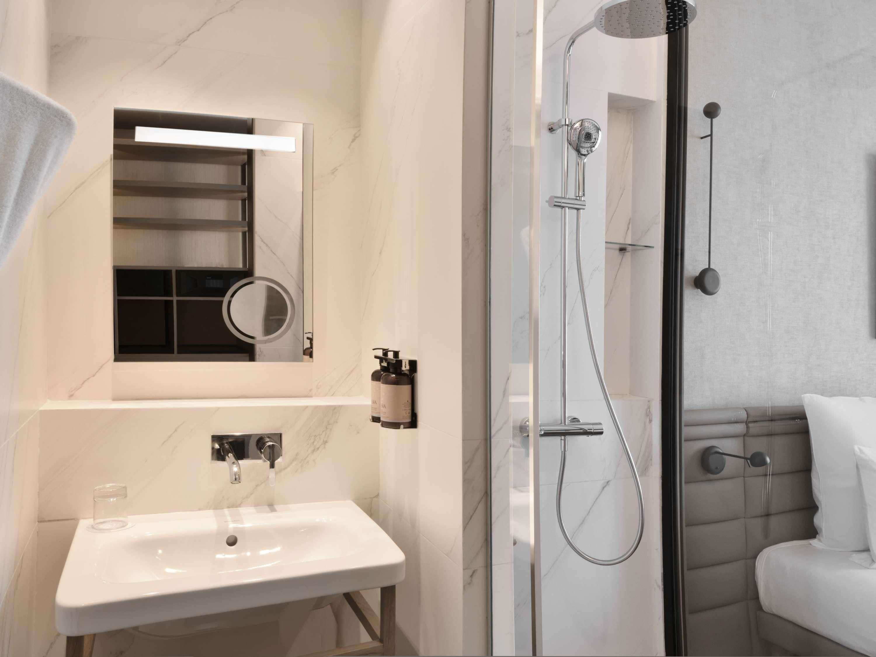 A modern bathroom with a glass-enclosed shower, a white sink, and a mirror above the sink.