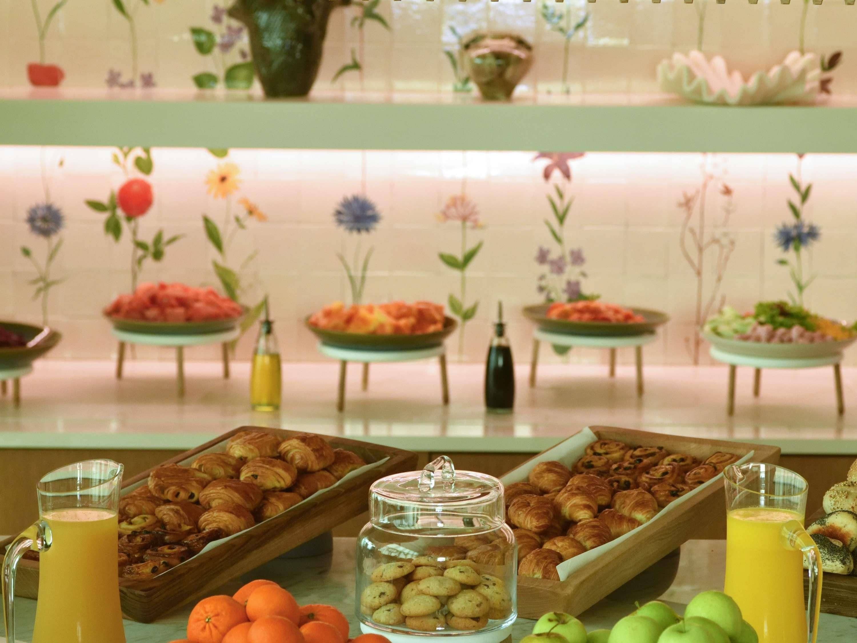 A buffet with various food items, including fruits, pastries, and beverages.