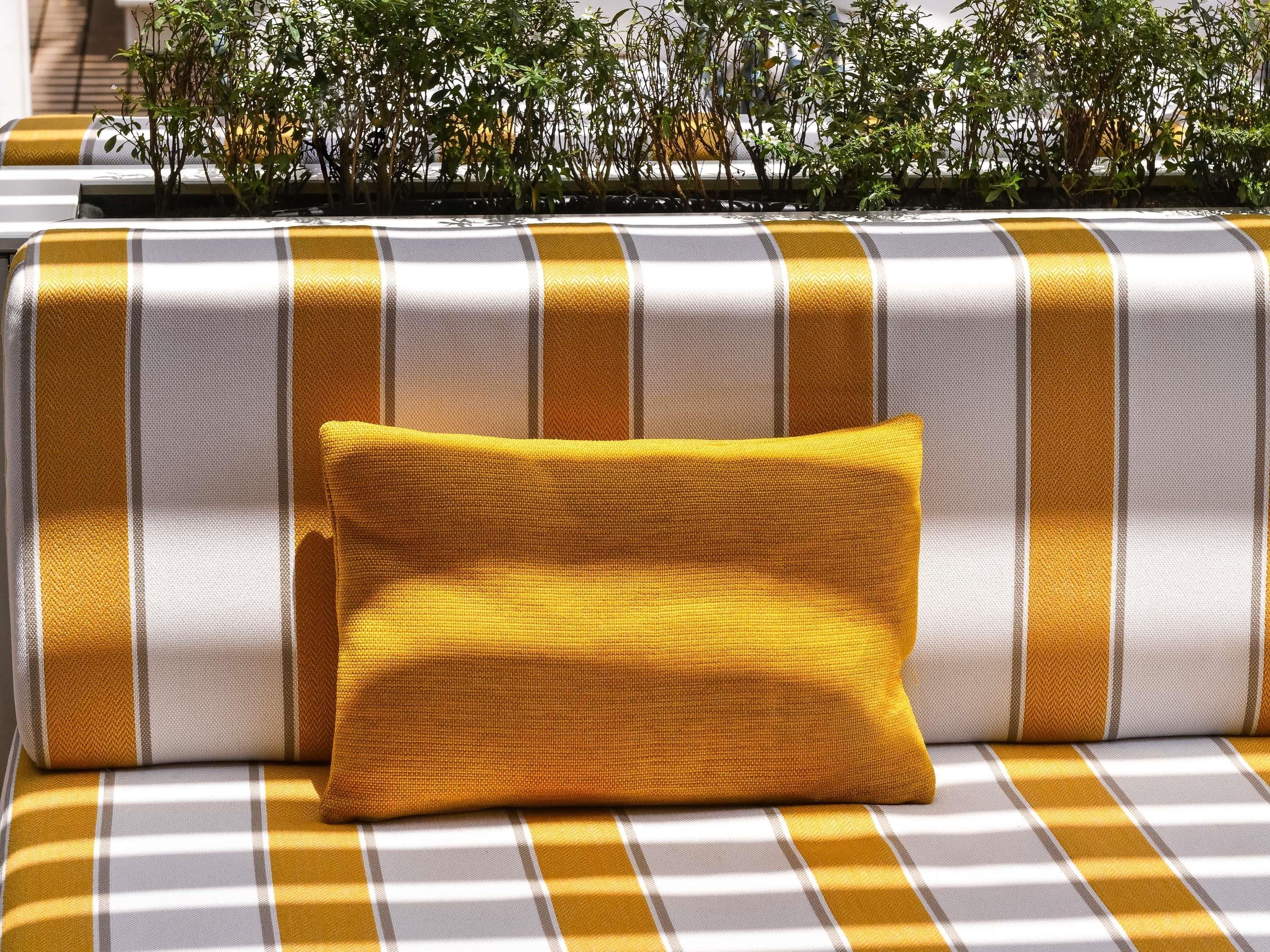 A sofa with a yellow pillow and a striped cushion.