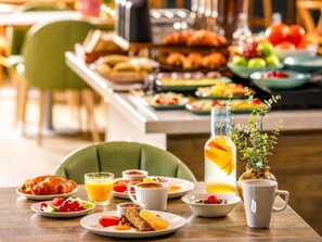 A breakfast setting with plates of food, a glass of orange juice, and a mug with a tea bag. - Novotel Abidjan Marcory (Abidjan)