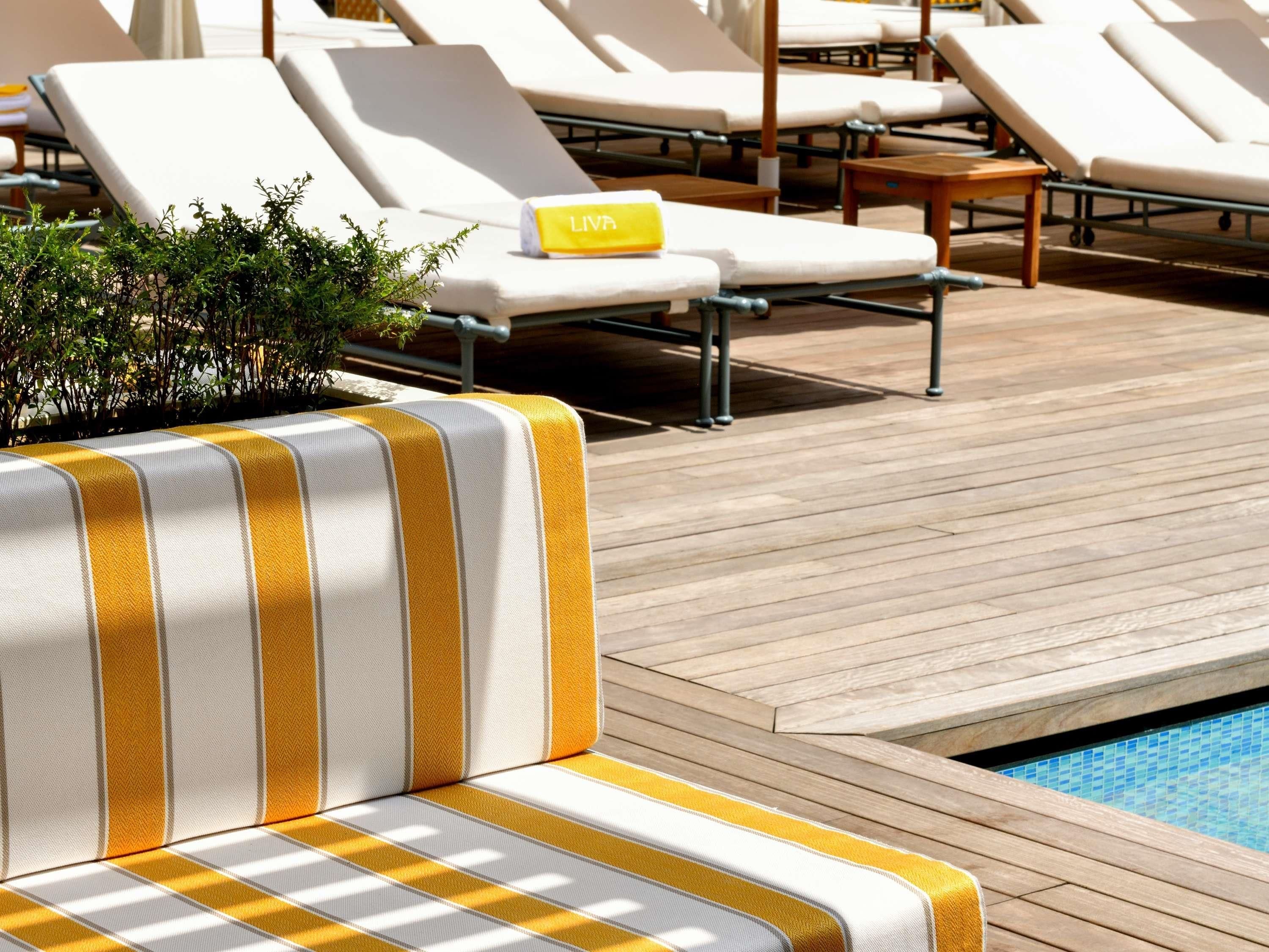 A poolside area with lounge chairs and a wooden deck.