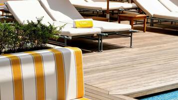 A poolside area with lounge chairs and a wooden deck.