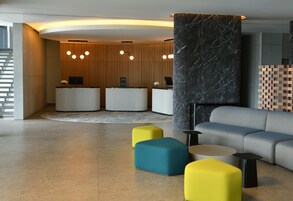 Una moderna zona de recepción con un panel de pared de madera, dos mostradores y un sofá gris.