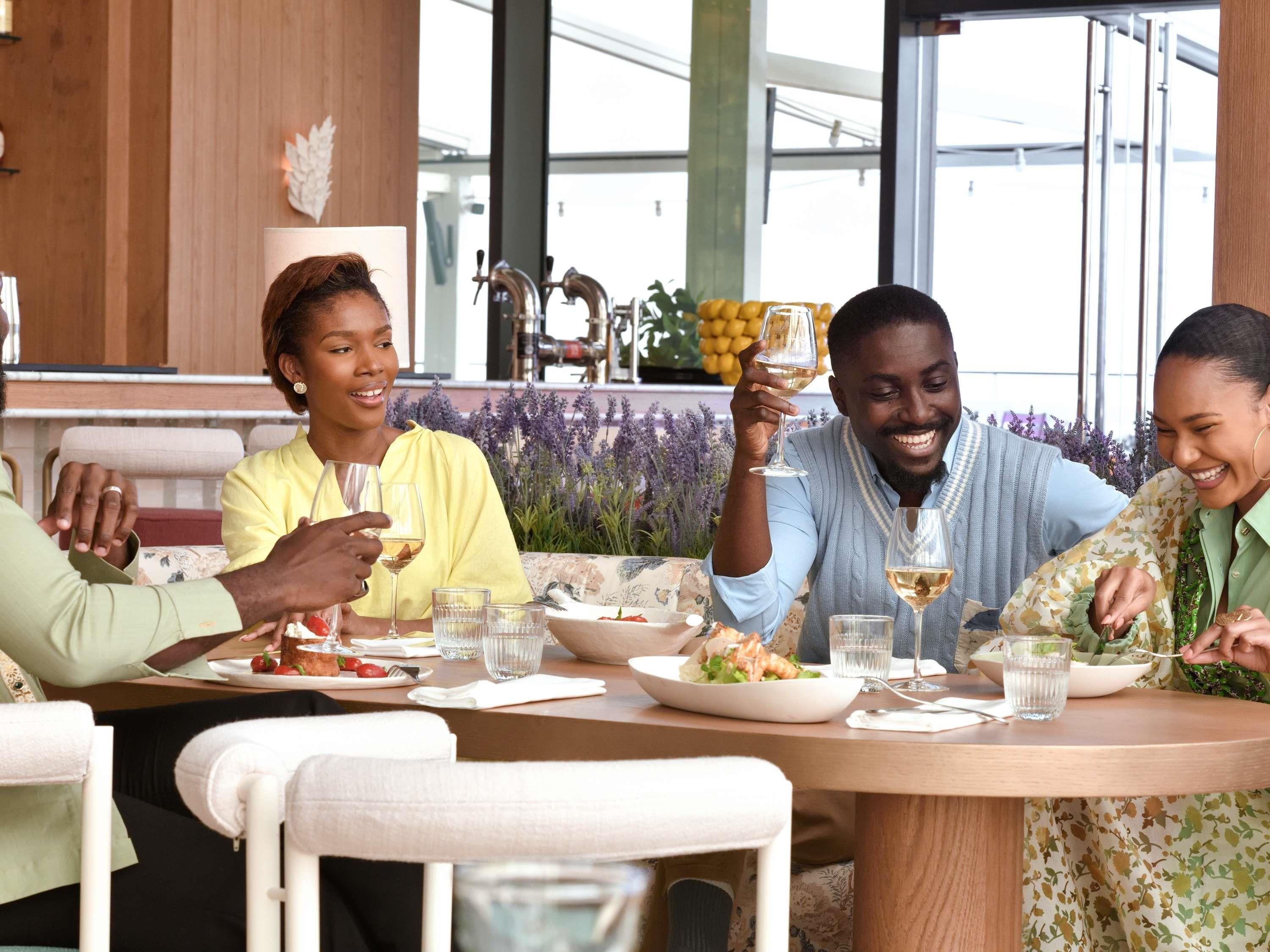 A group of people dining at a table in a modern restaurant with large windows and a view of the city.