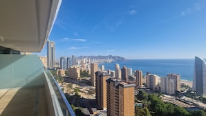 Um edifício alto com vista para a paisagem costeira, incluindo uma praia e um céu azul límpido.