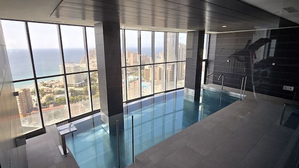 Piscina interior moderna com grandes janelas que oferecem vista para a cidade.