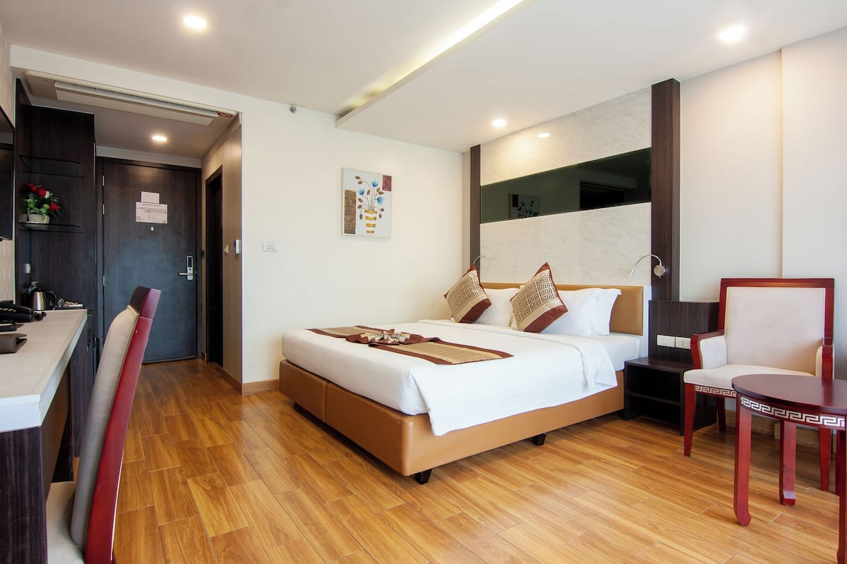 Una habitación de hotel moderna con cama, mesita de noche, sillón y escritorio con silla.