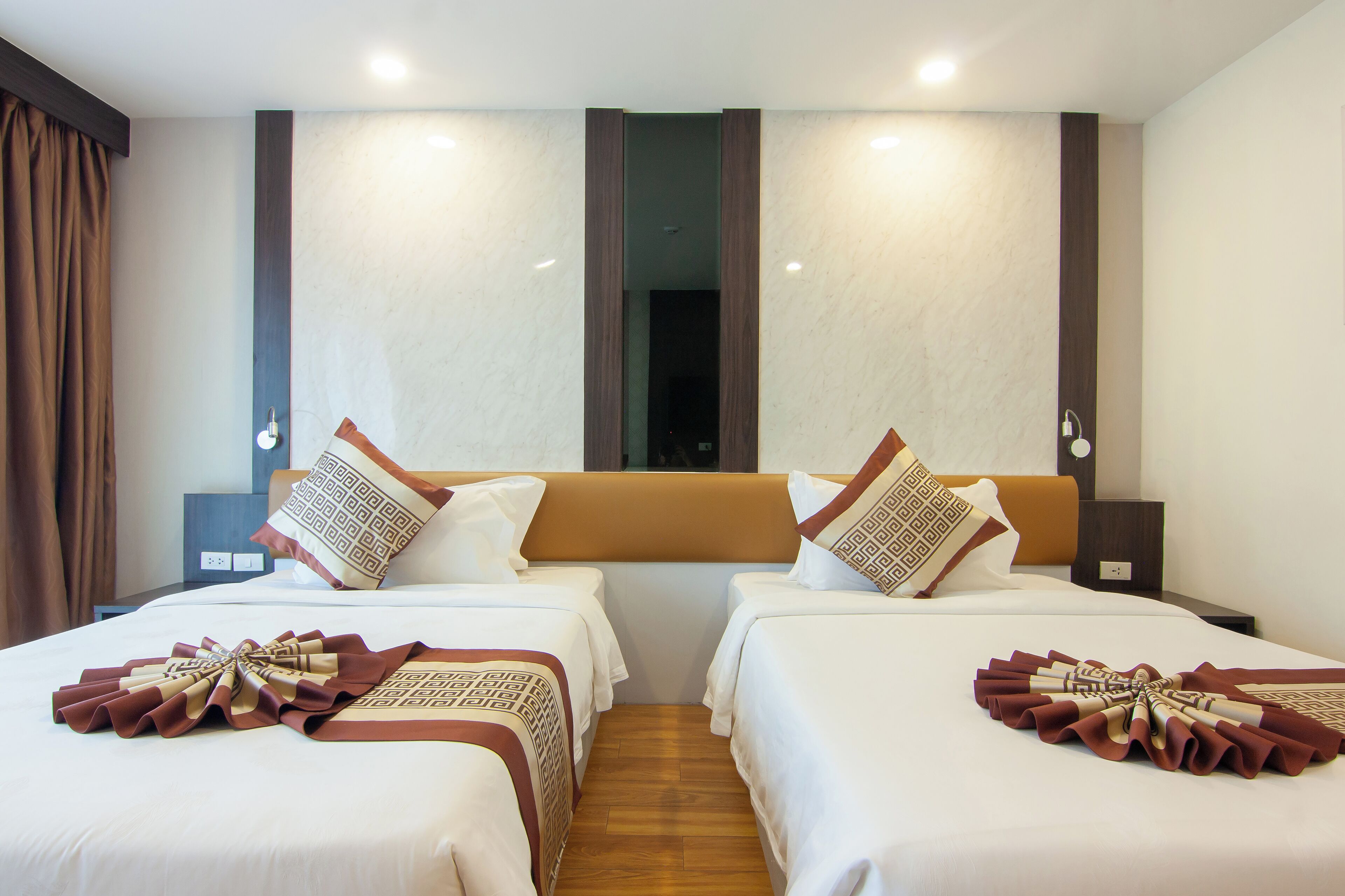 Ein Hotelzimmer mit zwei Betten, einem Holzkopfende und einem großen Fenster.