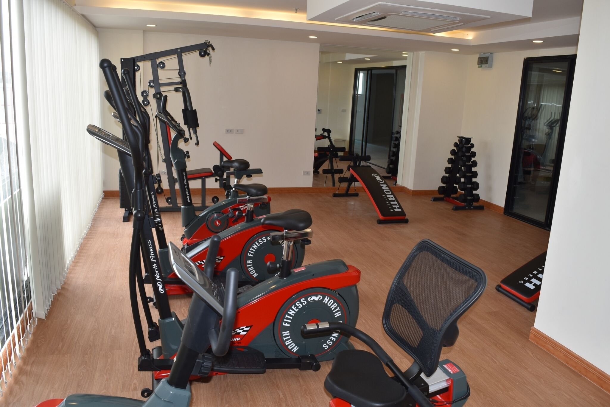 Una palestra con macchinari cardio, attrezzature per sollevamento pesi e uno specchio.