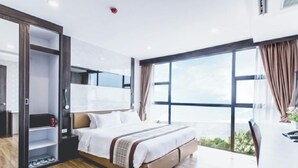 Habitación de hotel moderna con una cama grande, un escritorio y vistas al exterior.