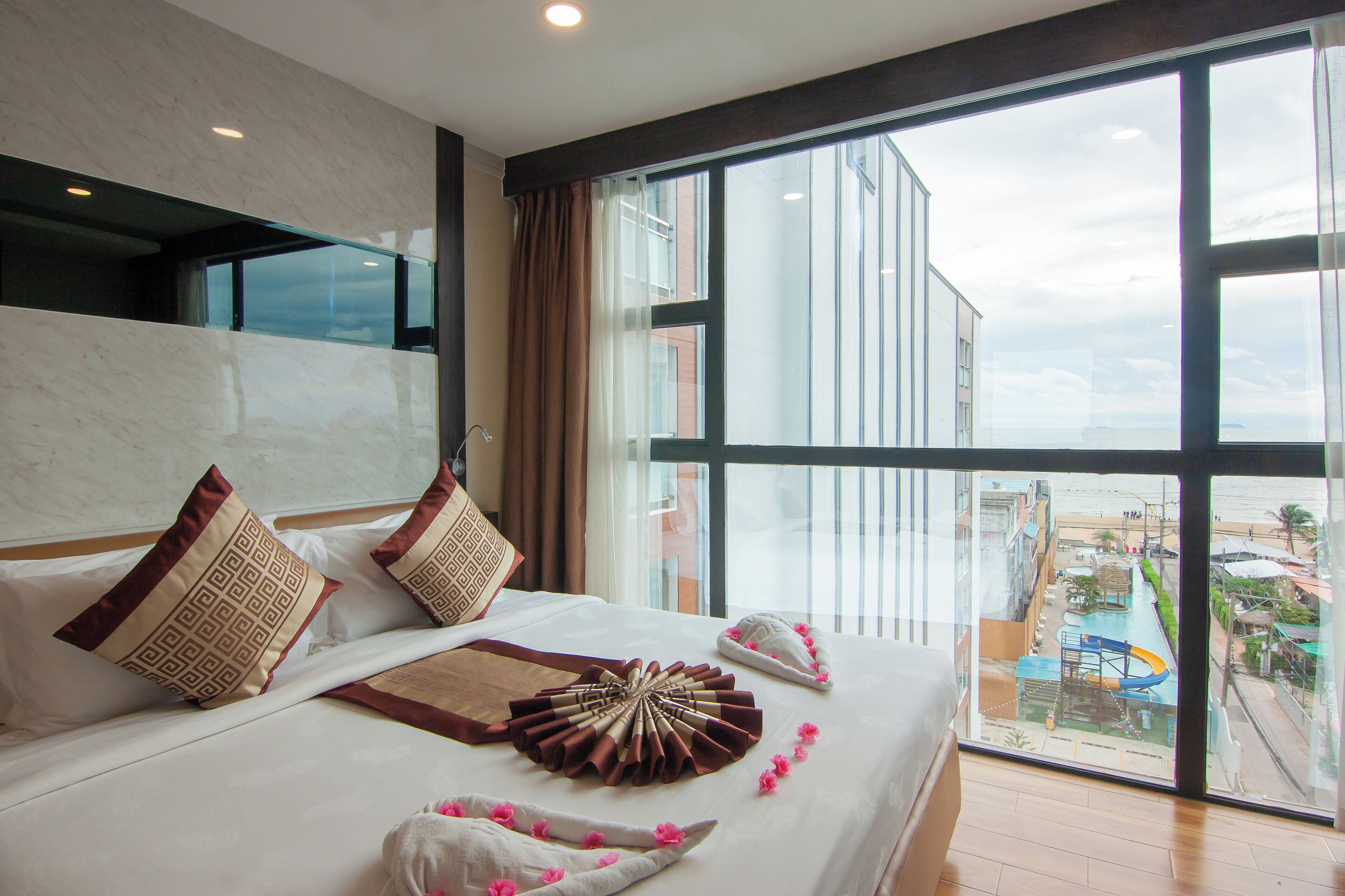 A hotel room with a large bed, a view of a water park, and a balcony with a railing.