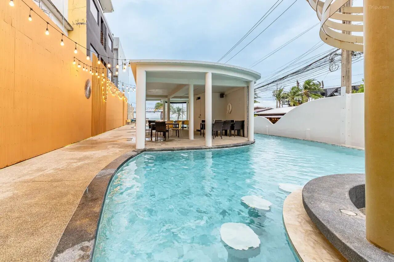 A pool area with a covered seating area, a lounge with tables and chairs, and a clear view of the pool.