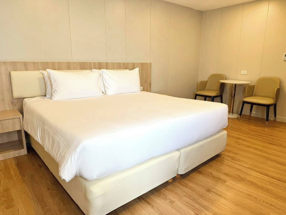 Een moderne hotelkamer met een groot bed, een tafeltje, twee stoelen en een houten vloer.