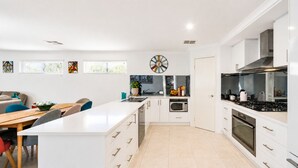 Una cucina moderna con mobili bianchi, un'isola centrale, un forno a microonde e un fornello.