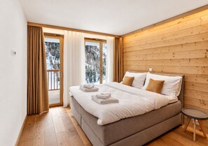 Una camera da letto con un letto grande, pareti in legno e vista sugli alberi dalla finestra.