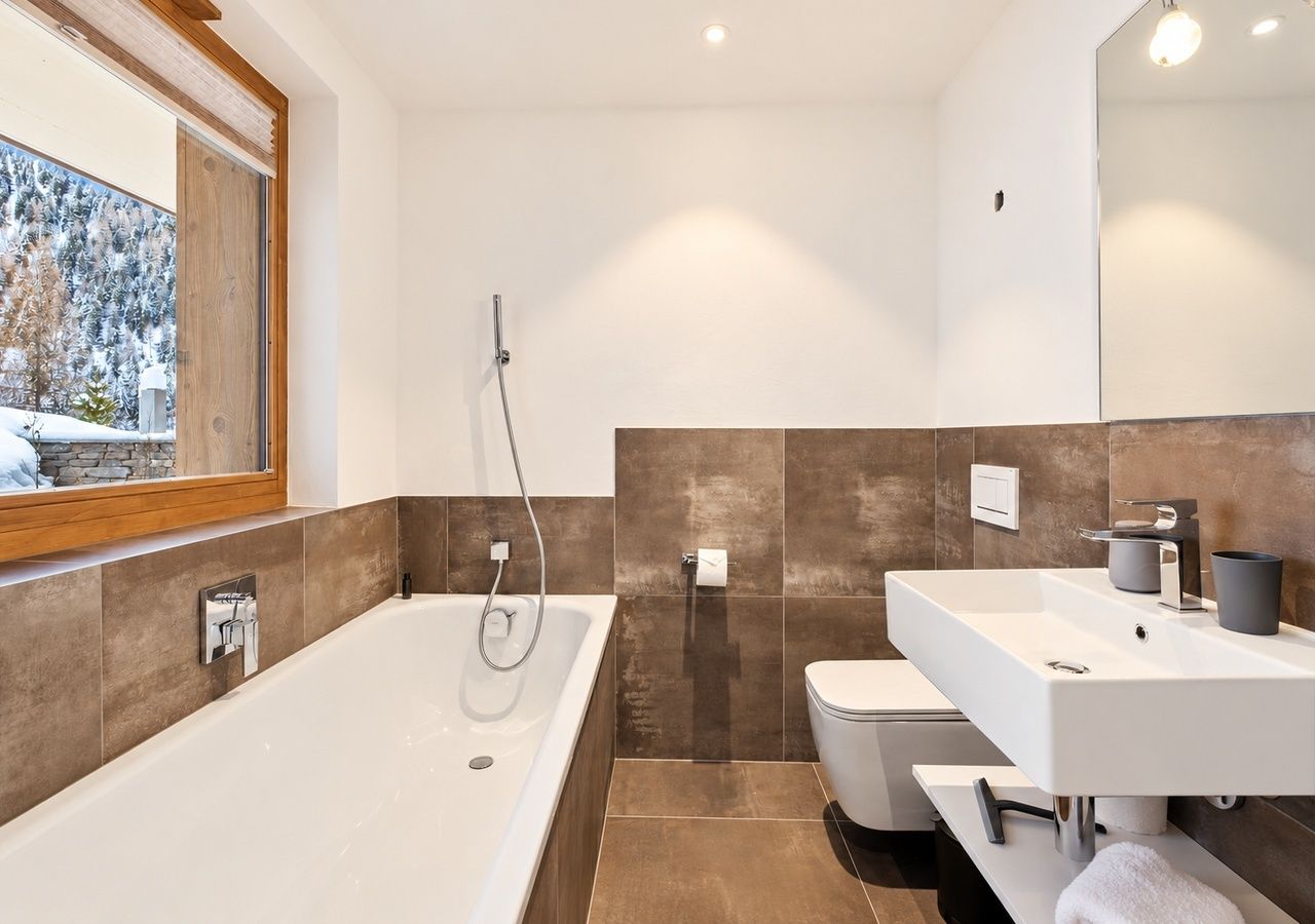 Een moderne badkamer met een groot ligbad, toilet en wastafel.