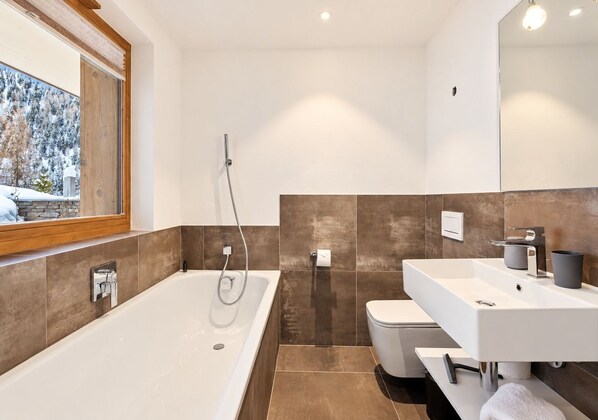 A modern bathroom with a large bathtub, a toilet, and a sink.