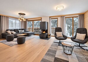 Ein modernes Wohnzimmer mit Kamin, Sofas, Sesseln und einem Couchtisch.