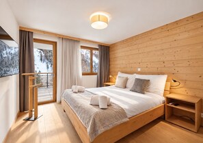 Ein modernes Schlafzimmer mit einem hölzernen Bett, einem Nachttisch und einem großen Fenster mit Vorhängen.