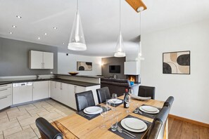 A modern kitchen with white cabinets, a dining table set for four, and pendant lighting. - Beautiful apartment at The Lodge Champéry - By Mrs Miggins (Champéry)