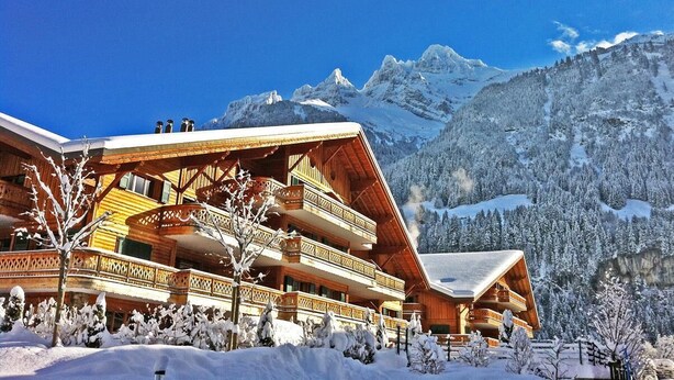A wooden chalet with multiple balconies, surrounded by snow-covered trees and mountains. - Beautiful apartment at The Lodge Champéry - By Mrs Miggins (Champéry)