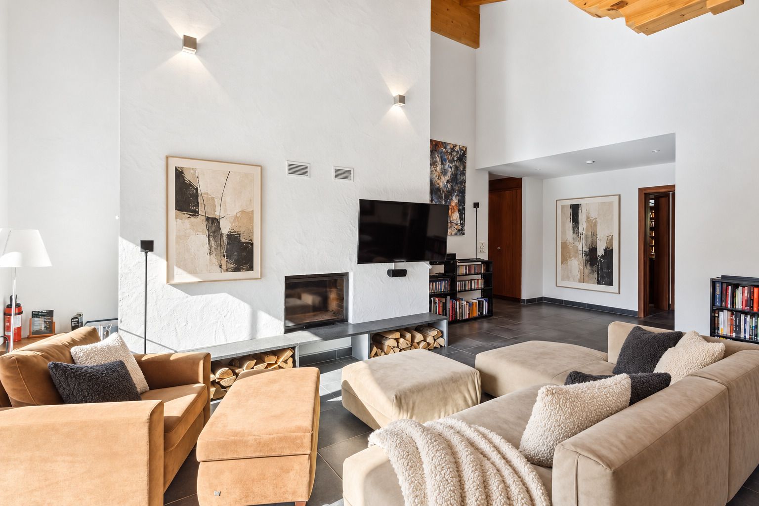 Ein modernes Wohnzimmer mit Kamin, Fernseher und Bücherregal.