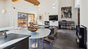 A modern living room with a round table, seating, a bookshelf, a TV, and a painting on the wall. - Sublime duplex with mountain view The Lodge Champéry - By Mrs Miggins (Champéry)