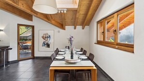 A dining area with a wooden table set for four, a large window with wooden shutters, and a skylight above. - Sublime duplex with mountain view The Lodge Champéry - By Mrs Miggins (Champéry)