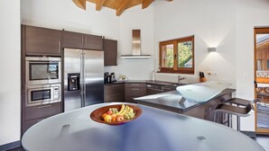 A modern kitchen with stainless steel appliances, a large island with a bowl of fruit, and a window providing natural light. - Sublime duplex with mountain view The Lodge Champéry - By Mrs Miggins (Champéry)