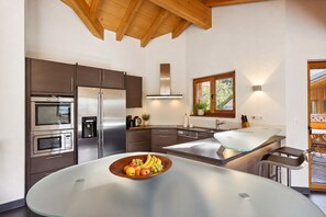 A modern kitchen with stainless steel appliances, a glass-top island, and a view of the outdoors.