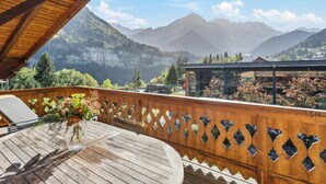 A wooden deck with a round table and chairs, overlooking a mountainous landscape with a clear sky. - Sublime duplex with mountain view The Lodge Champéry - By Mrs Miggins (Champéry)