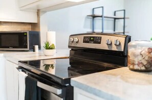 Una cocina moderna con una placa de inducción negra, un microondas y una campana extractora de acero inoxidable.