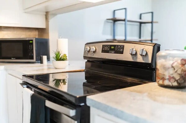A modern kitchen with a black induction cooktop, a microwave, and a stainless steel range hood.
