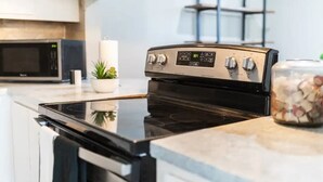 Une cuisine avec un four noir, un four à micro-ondes et une plante en pot.