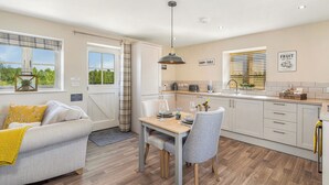 Une cuisine moderne avec une table de style rustique, un coin repas avec un canapé et une vue sur la verdure à l’extérieur.
