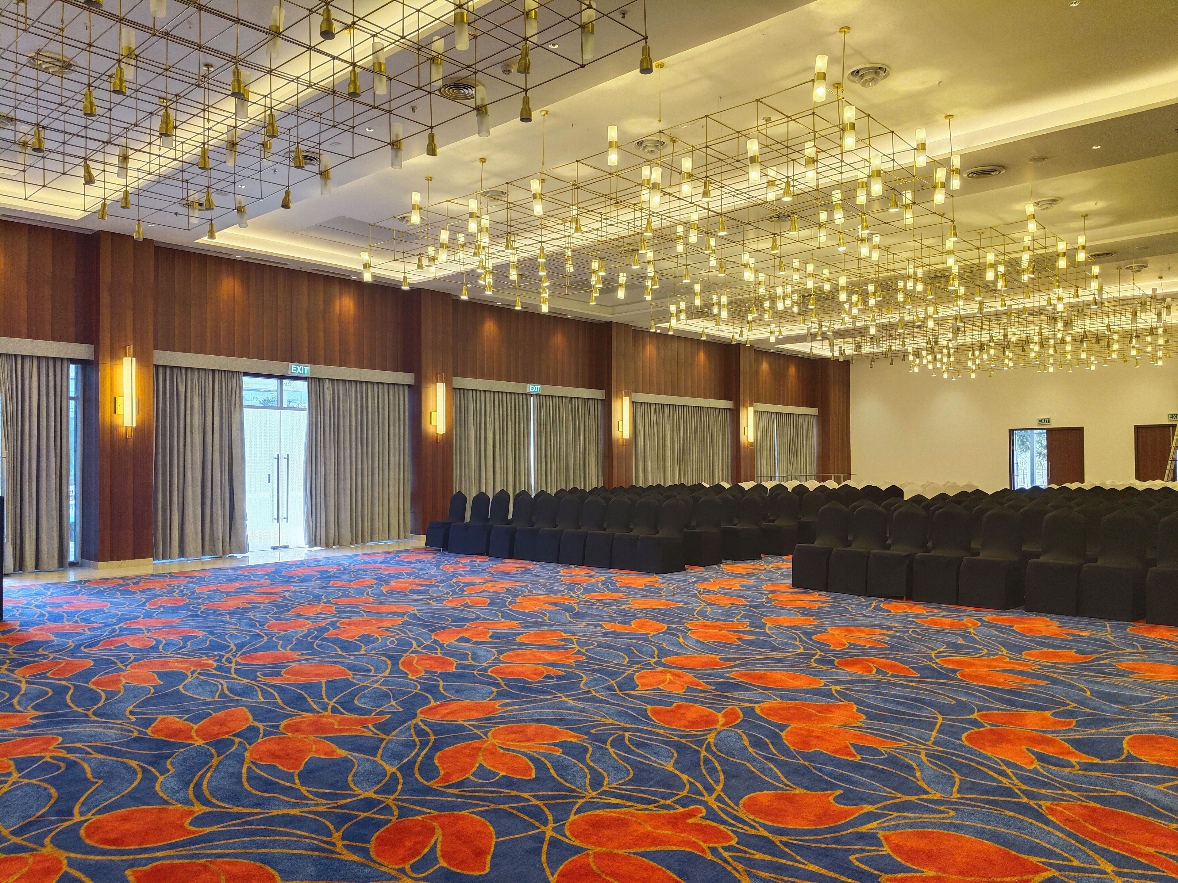 A large conference room with rows of chairs, a patterned carpet, and a modern chandelier.